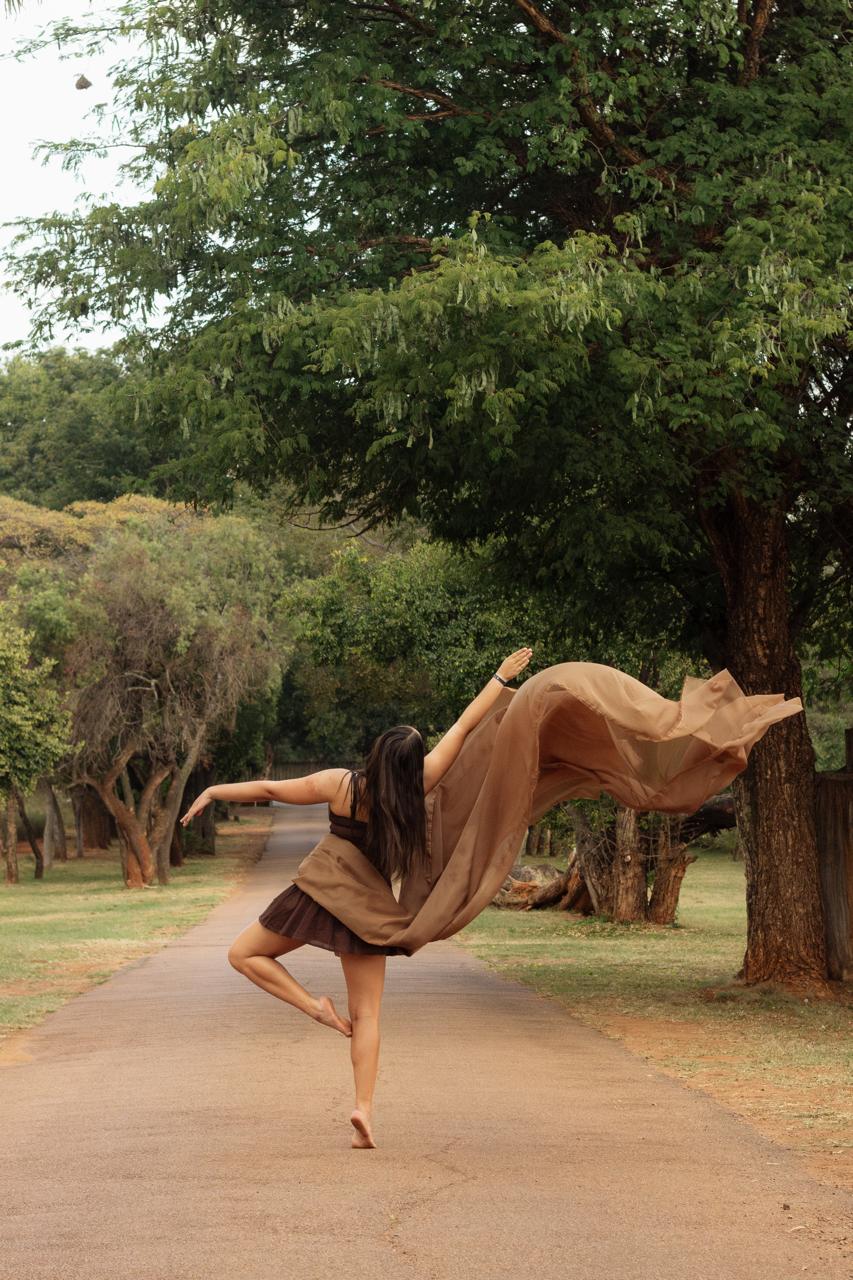 A dancer balancing on one leg as fabric trails behind her